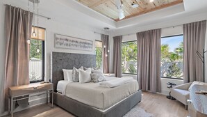 A modern bedroom with a large bed, a desk, and a view of greenery outside. - Private Heated Pool, Single-Level Home, Golf Cart (Inlet Beach)