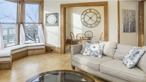 A cozy living room with a sofa, a round coffee table, and a dining area with chairs. - Northern Michigan gem in a beautiful beach town. (Frankfort)