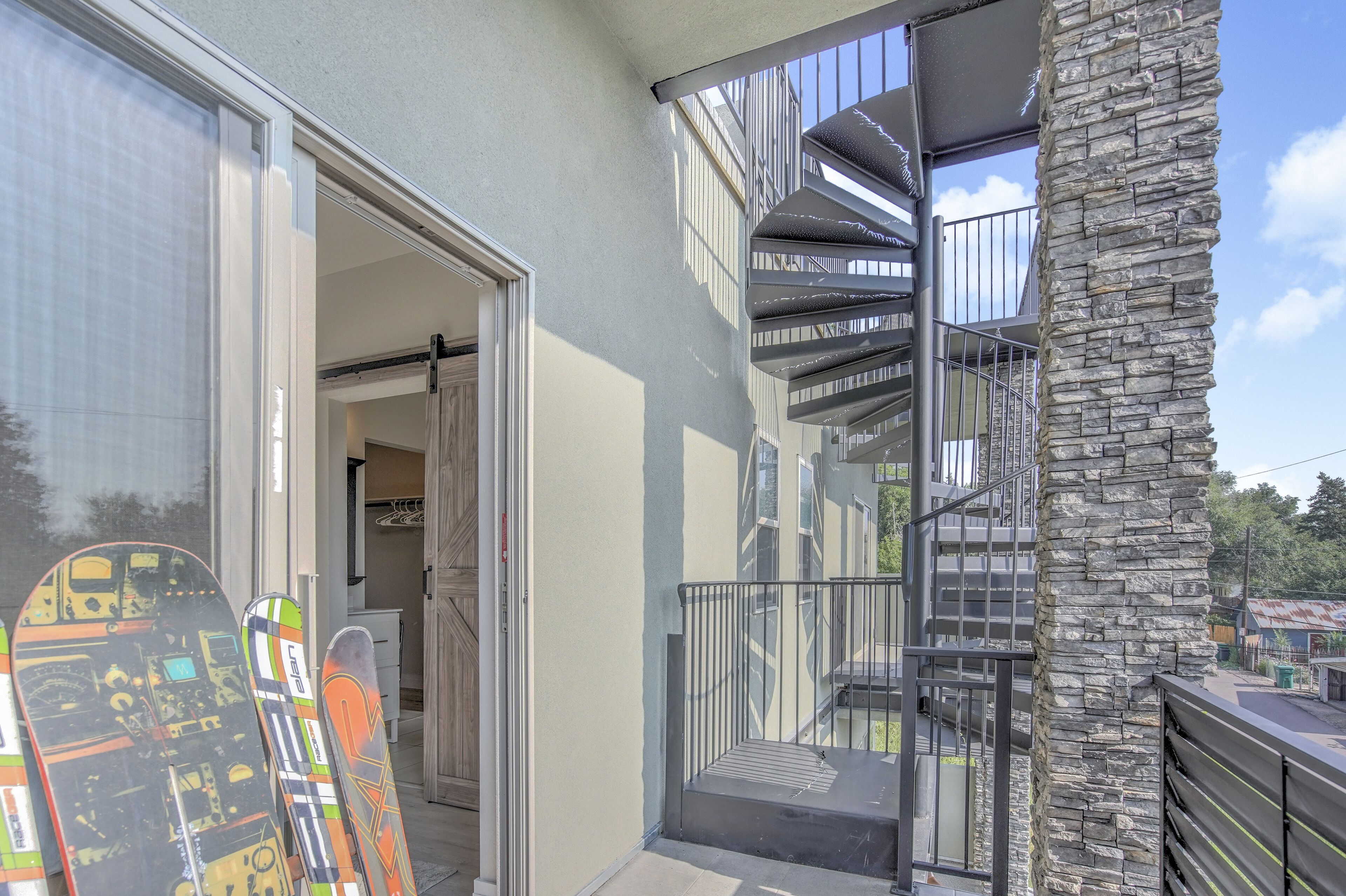 Un bâtiment moderne avec un pilier en pierre, une porte en verre donnant sur une pièce et un escalier en colimaçon.