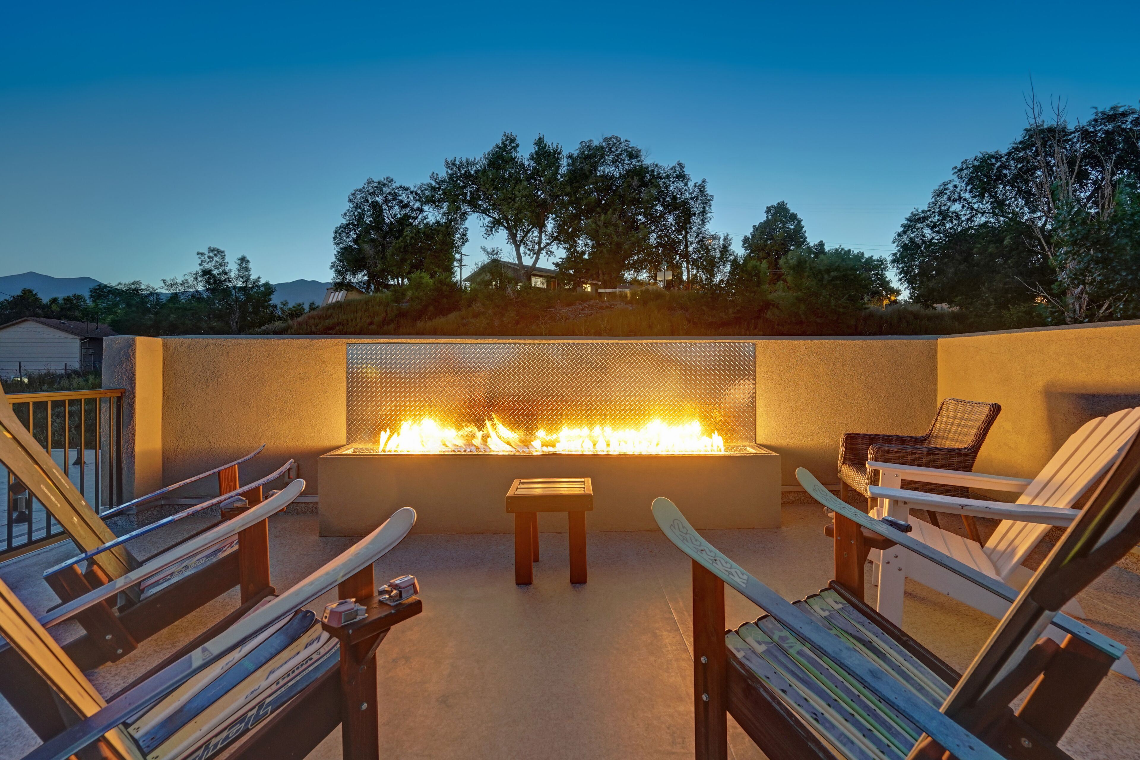 An outdoor seating area with a fire feature, wooden chairs, and a small table.