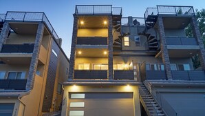 Un edificio residenziale a più piani con garage, balconi e una scala a chiocciola.
