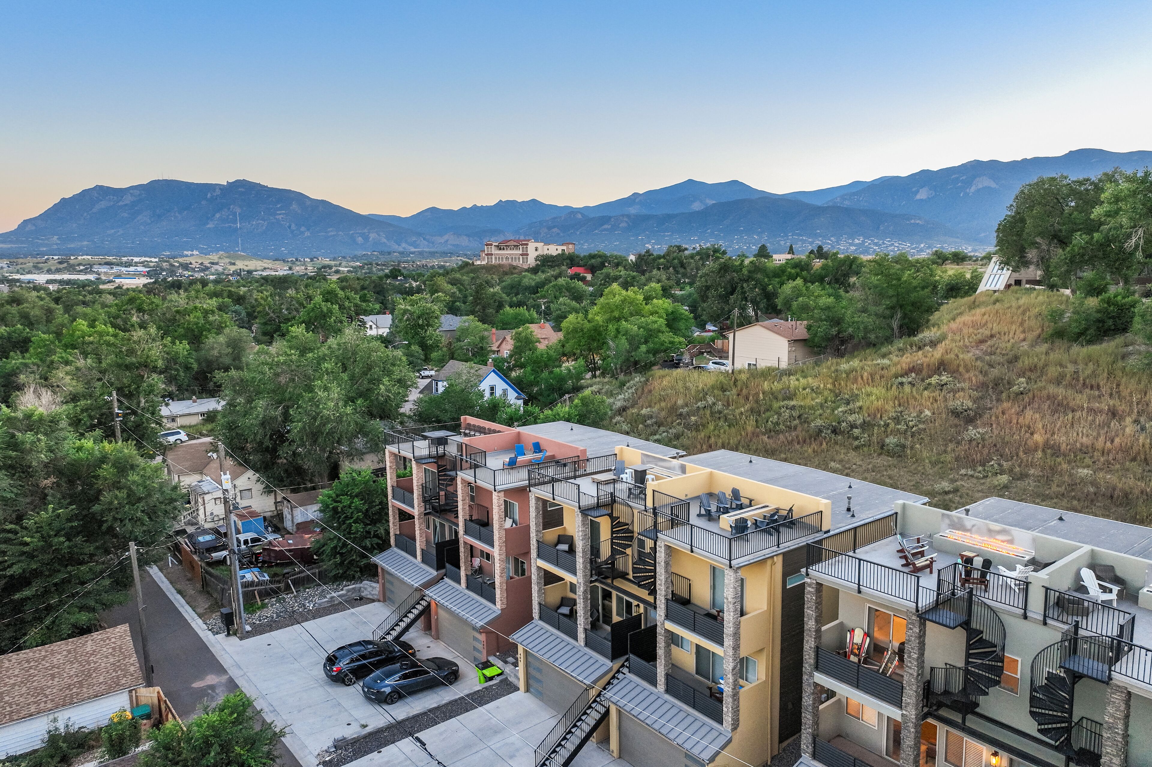 A multi-story building with balconies, a fire pit, and a view of mountains.