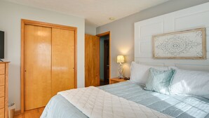 A bedroom with a bed, wooden wardrobe, bedside table with lamp, and a decorative wall piece. - Large Home w/ Deck & Grill ~ 9 Mi to Virginia Tech (Christiansburg)
