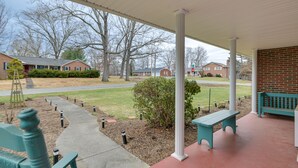 A covered porch with benches, a pathway, and a brick building in the background. - Large Home w/ Deck & Grill ~ 9 Mi to Virginia Tech (Christiansburg)