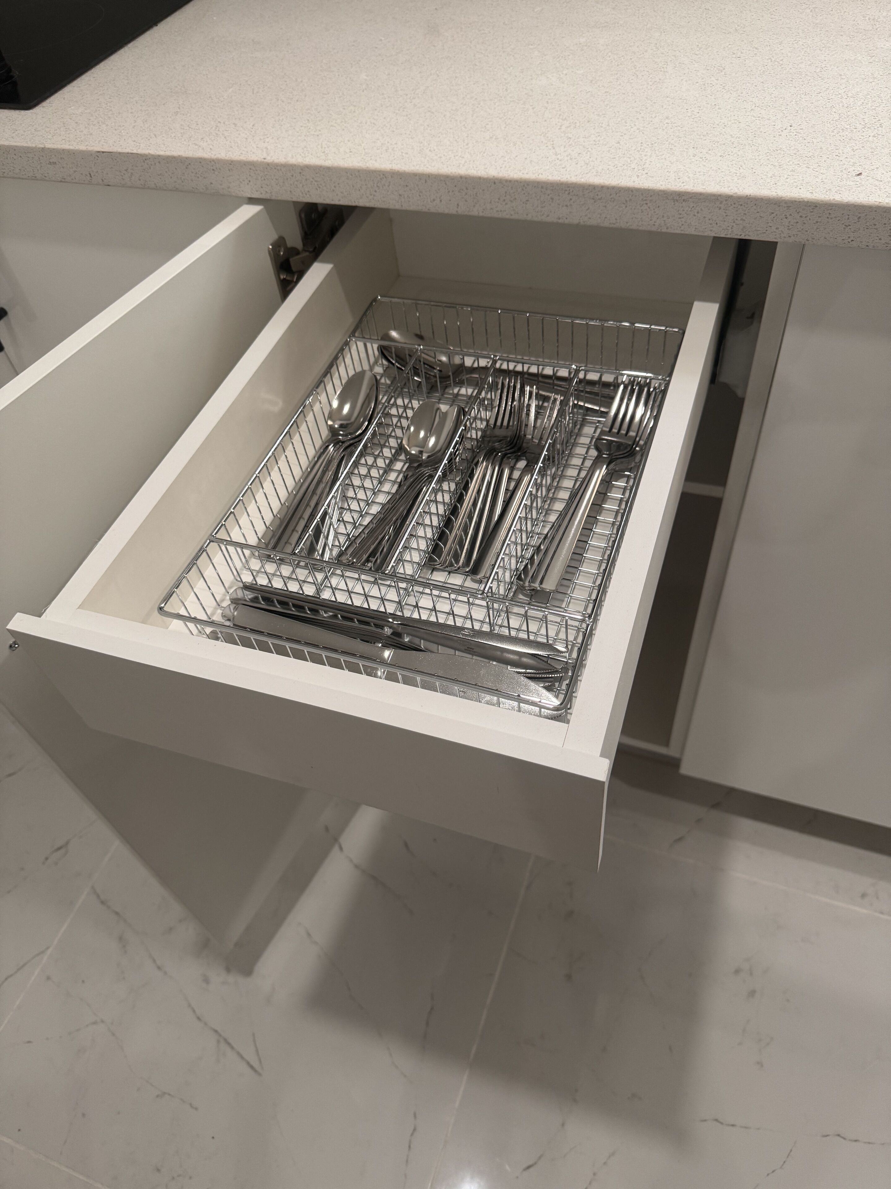 Un cajón de cocina con un organizador de utensilios que contiene cucharas, tenedores, cuchillos y una espátula.