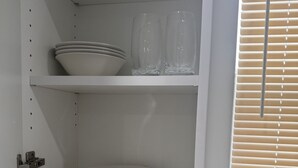 Una cocina con armarios blancos, salpicadero de azulejos y una ventana con persianas.