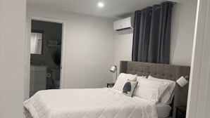 Un dormitorio con cama, mesita de noche, lámpara, ventilador de techo y aire acondicionado.