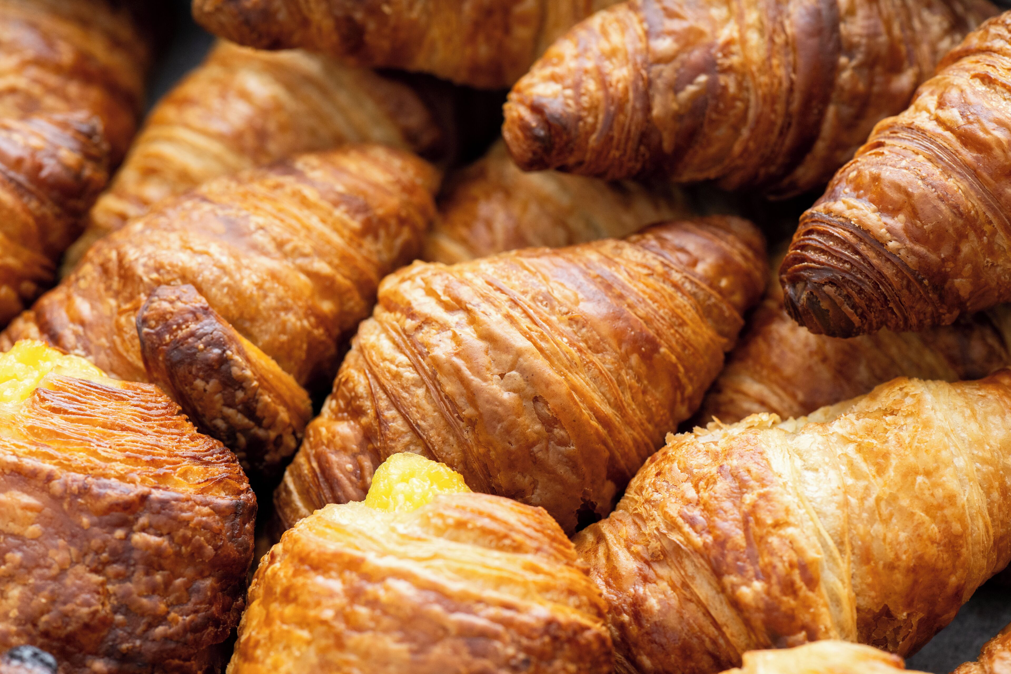A close-up of golden-brown croissants with visible layers and a glossy finish.