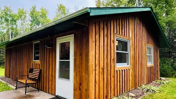 Eine Holzhütte mit Tür, Fenstern und einer Bank davor.