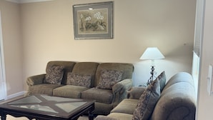 A living room with a sectional sofa, a glass-top coffee table, and a framed botanical print on the wall. - La Casita, Las Vegas (Las Vegas)