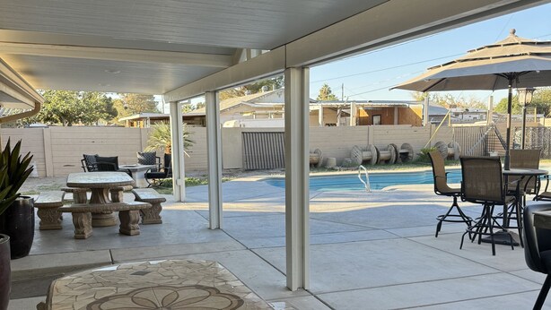 An outdoor patio area with a large mosaic table, several chairs, and a pool in the background. - La Casita, Las Vegas (Las Vegas)