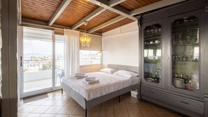 Un dormitorio con una cama, un aparador con vajilla y un balcón con vistas.