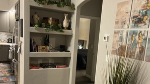 Une cuisine moderne dotée d’un réfrigérateur encastré, un coin repas avec une table et des chaises, et un salon agrémenté d’une cheminée et d’œuvres d’art au mur.