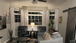Un salon comprenant un canapé, deux fauteuils, une table basse, un téléviseur et un ventilateur de plafond.