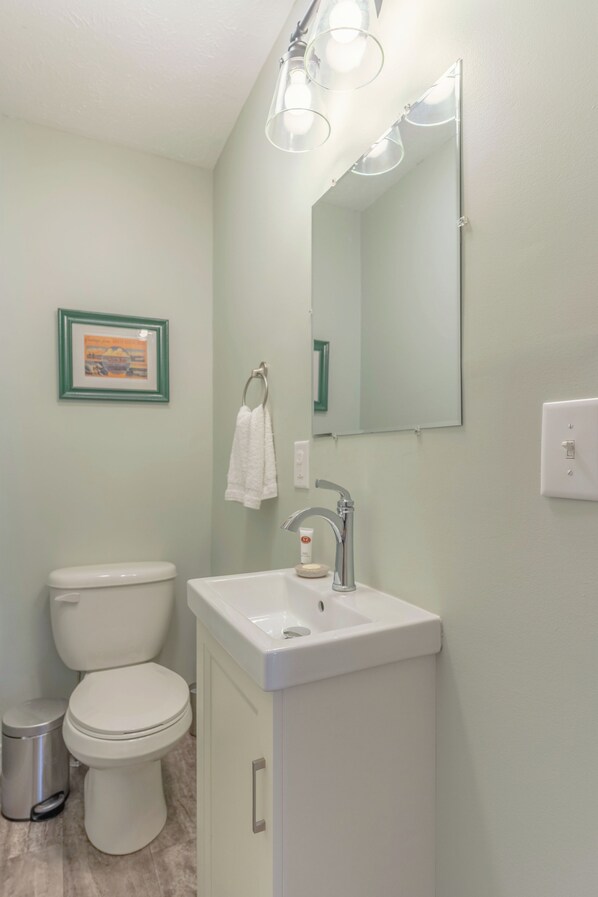 A bathroom with a toilet, sink, and mirror.