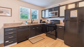A modern kitchen with dark cabinetry, stainless steel appliances, and a granite countertop.