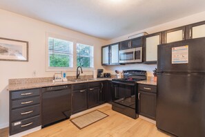 A modern kitchen with dark cabinetry, stainless steel appliances, and a granite countertop.