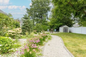 A garden pathway leading to a shed with outdoor seating.