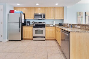 A kitchen with wooden cabinets, stainless steel appliances, and a granite countertop.