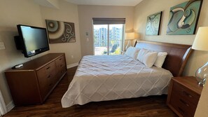 A hotel room with a bed, wooden nightstands, a TV, and artwork on the walls.
