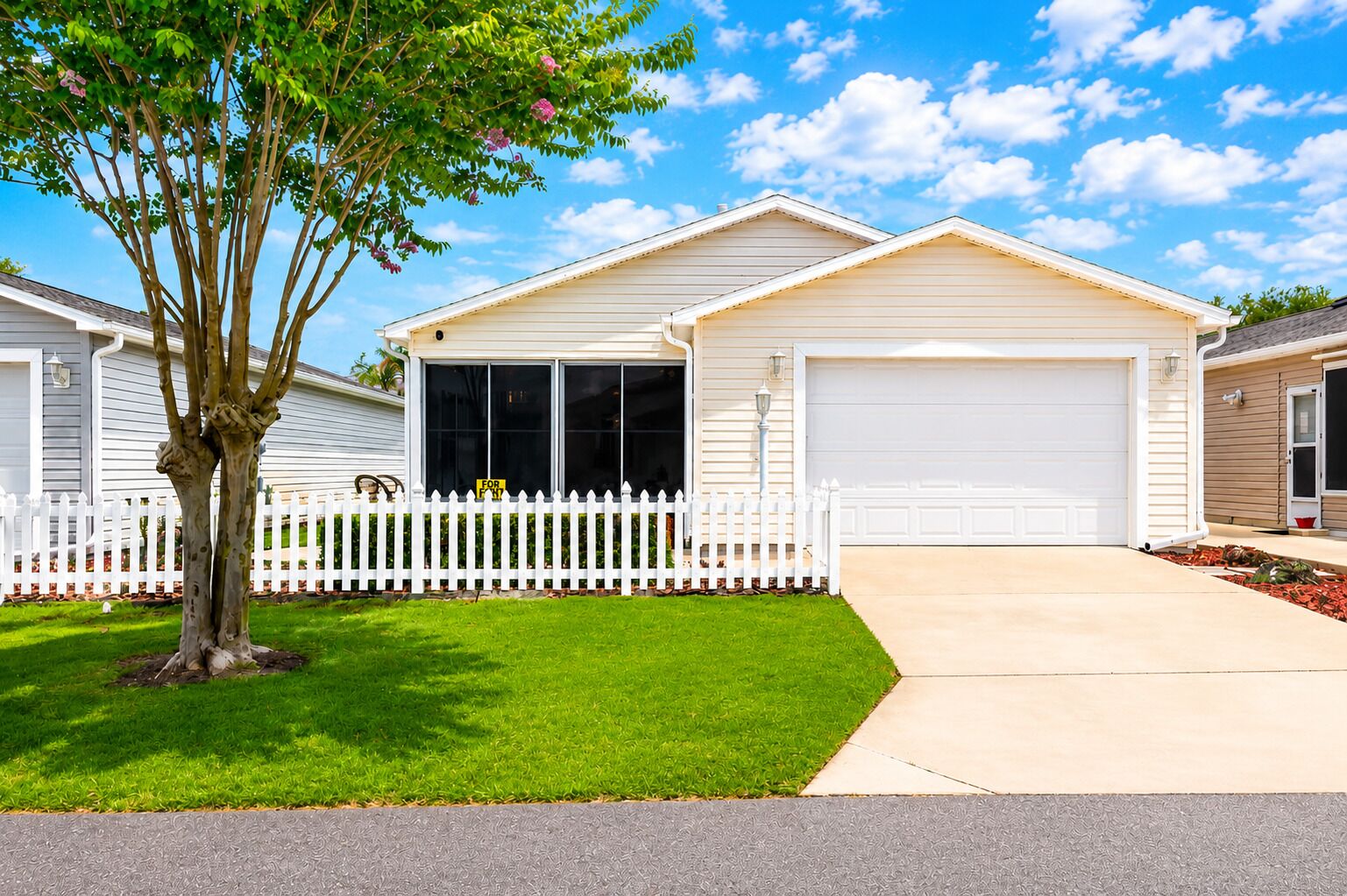 A two-story house with a white garage door, a front porch, and a tree in the front yard.
