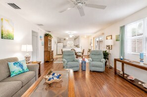 Una sala de estar con sofá, dos sillones, una mesa de centro y una zona de comedor con mesa y sillas.