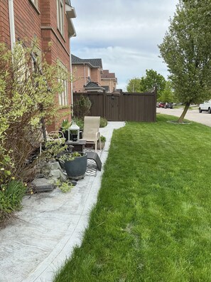 A residential backyard with a patio, a wooden fence, and a lawn. - Modern Cozy 2 BR Private Suite,5 Min drive -Creditview & Sandalwood Sports field (Brampton)