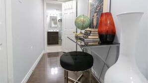 A hallway with a white door, a black stool, a globe, books, and a red vase on a shelf. - Modern Cozy 2 BR Private Suite,5 Min drive -Creditview & Sandalwood Sports field (Brampton)