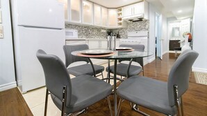 A modern kitchen with white cabinets, a glass dining table, and four grey chairs. - Modern Cozy 2 BR Private Suite,5 Min drive -Creditview & Sandalwood Sports field (Brampton)