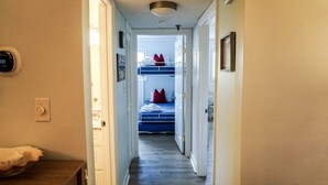 A narrow hallway leading to a room with bunk beds, a digital clock, and a small table with a cushion. - Just a walk to the beach, centrally located, multiple pools, family friendly. (Hilton Head Island)