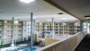 A multi-story hotel with a central courtyard featuring a swimming pool, lounge chairs, and a small garden area. - Just a walk to the beach, centrally located, multiple pools, family friendly. (Hilton Head Island)