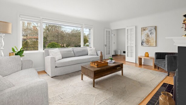 Een moderne woonkamer met een grijze bank, een houten salontafel en een open haard.