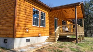 Une cabane en rondins dotée d’un porche et d’un escalier menant à l’entrée.