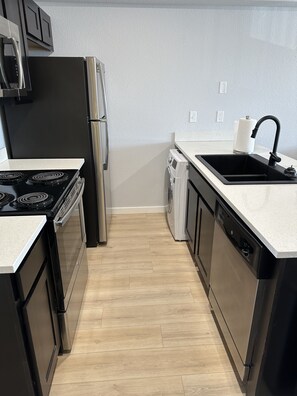A modern kitchen with stainless steel appliances, a dishwasher, and a sink. - Stadium View Condo (Manhattan)