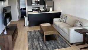 Ein modernes Wohnzimmer mit einer Couch, einem Couchtisch und einem Fernseher auf einem Holzschrank.