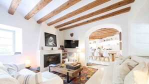 A living room with a fireplace, white sofas, a coffee table, and a colorful rug. - Es Clot (Deia)