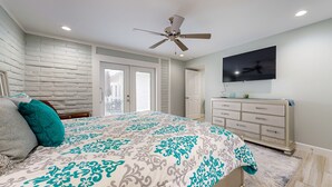 A bedroom with a bed, a ceiling fan, a TV, and a dresser. - Shared Pool, Golf Cart Boardwalk, Shared Grills (Port Aransas)