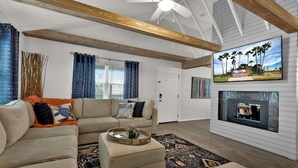 A living room with a sectional sofa, a coffee table, a fireplace, and a television mounted on the wall. - Private Home w/Private pool1/2 block from Beach! Stylish Interior! Dog friendly! (South Padre Island)