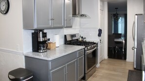 Una cocina moderna con armarios grises, horno integrado, cafetera y refrigerador de acero inoxidable.