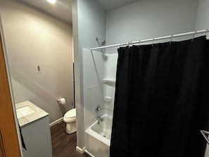 Een badkamer met douche, toilet en wastafel.