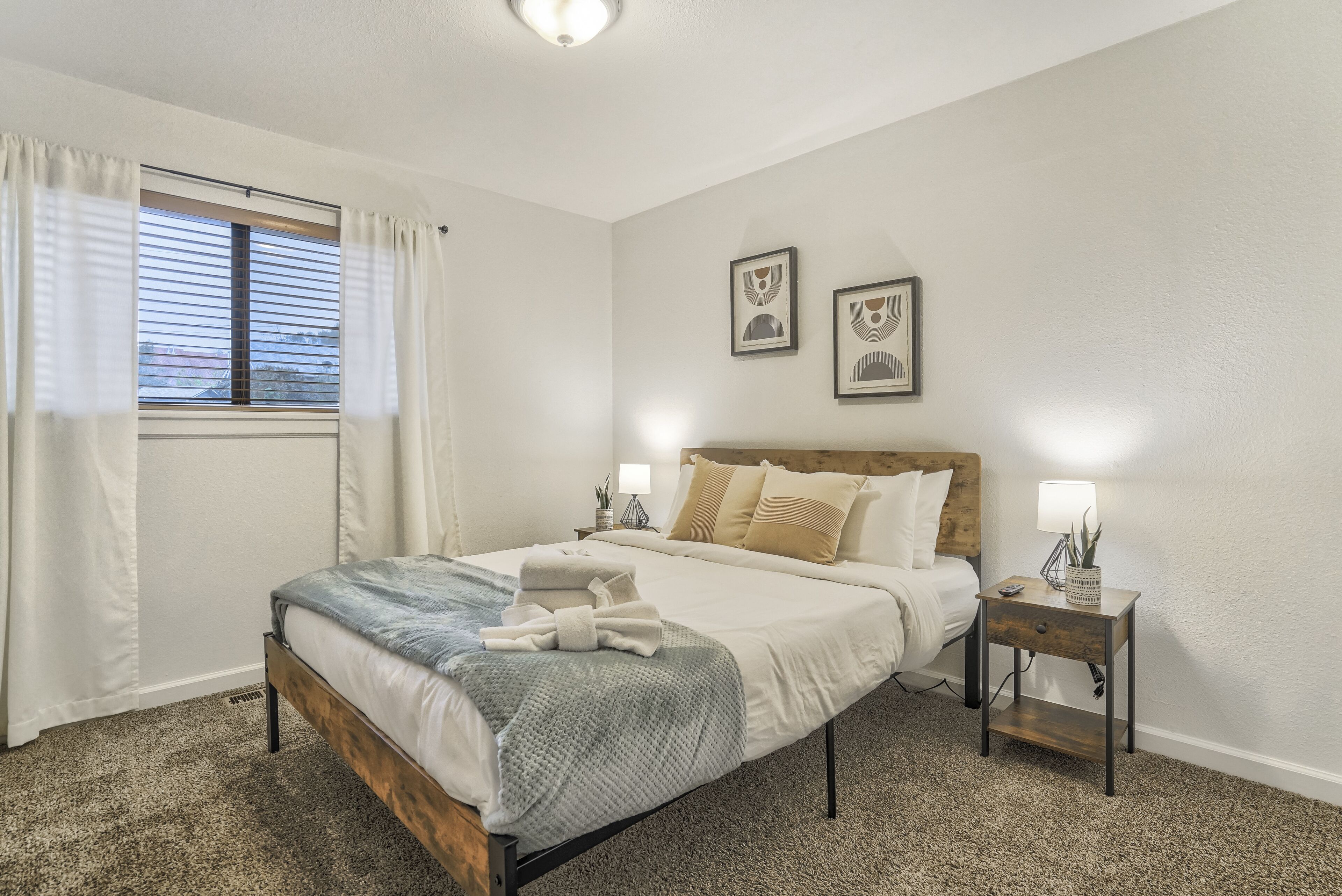 A bedroom with a bed, bedside tables, and a window with curtains.