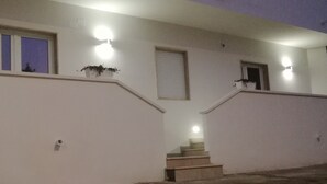 Fachada de um edifício com escadaria, janela com vista e luminárias na parede.
