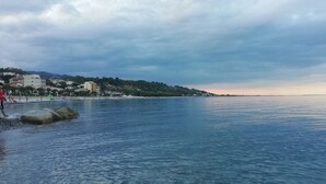 Vista costeira com céu claro, mar calmo e edifícios ao longo da praia.