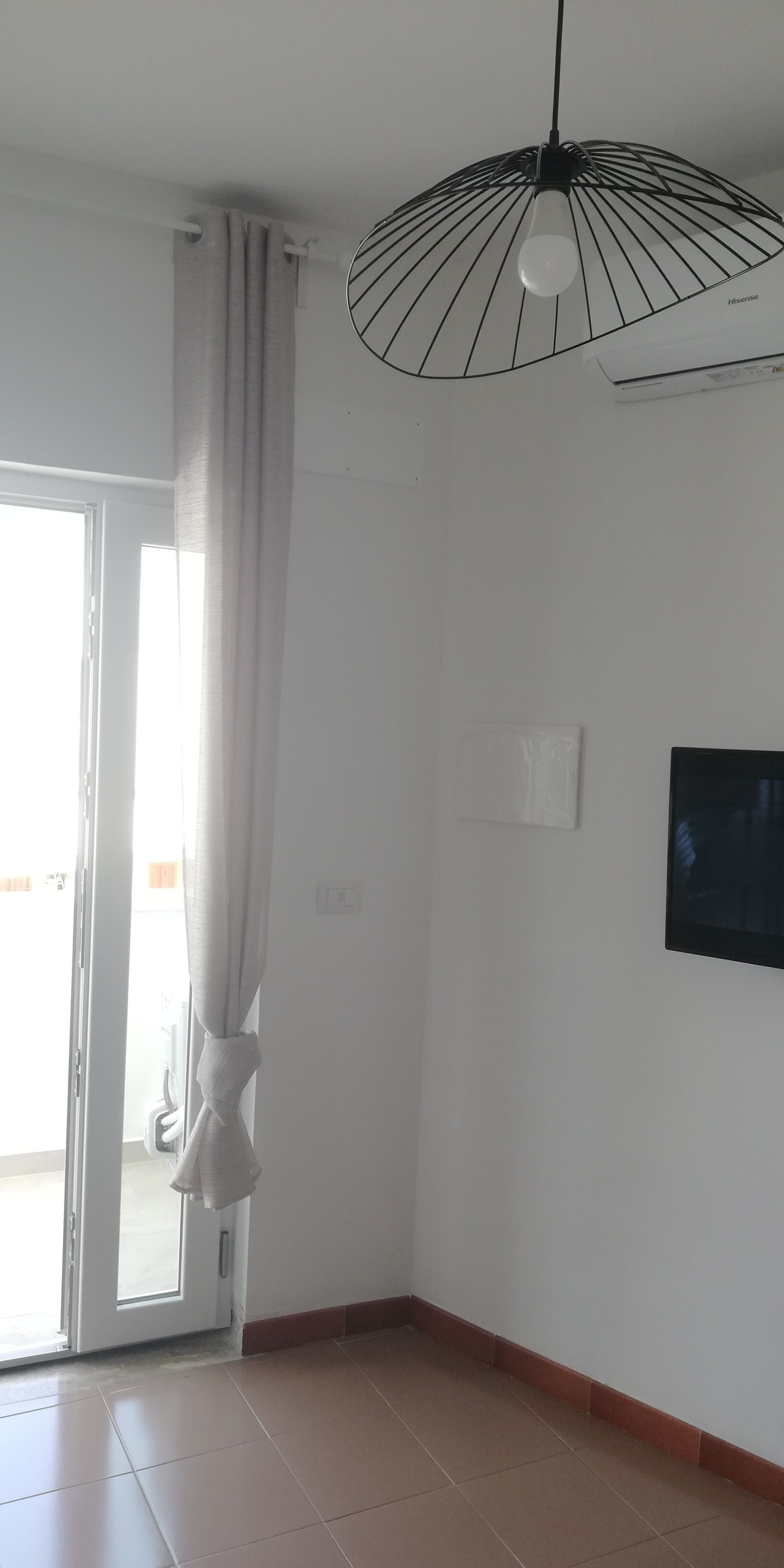 A room with a sliding glass door, a hanging pendant light, and a framed picture on the wall.