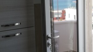 Quarto com porta de vidro deslizante que dá para uma varanda com vista para o mar.