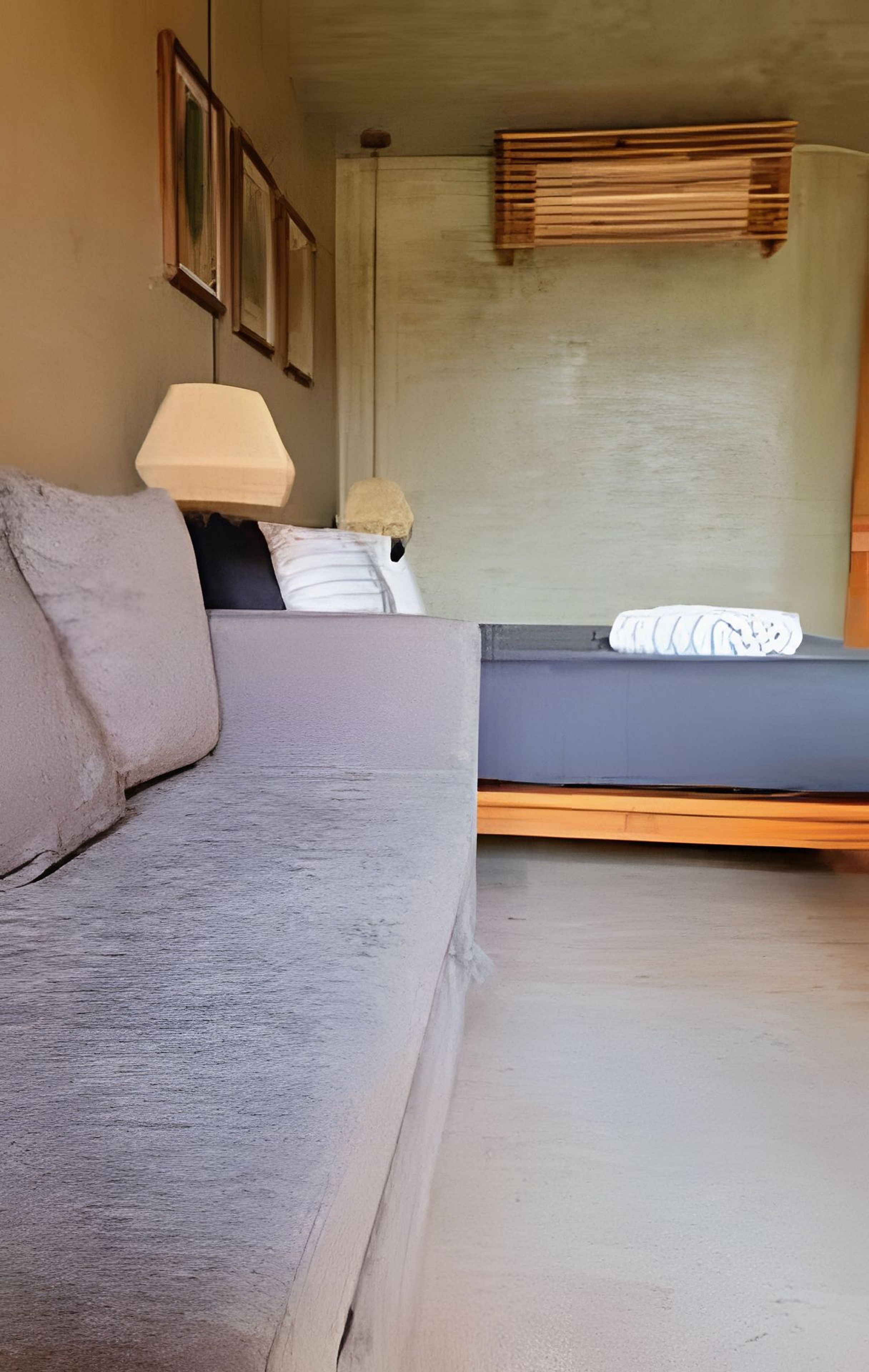 A room with a sofa, a bed, a wall-mounted shelf, and a framed picture.