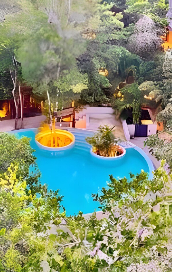 A pool with a circular design, surrounded by lush greenery and a wooden deck.
