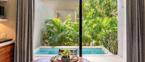 Comedor con vista a una piscina y abundante vegetación.