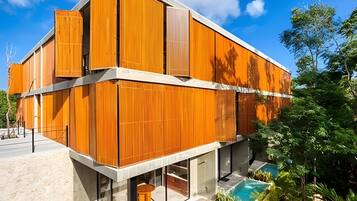 Un edificio moderno con facciata in legno, una piscina e un cielo sereno.