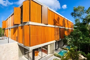 Ein modernes Gebäude mit Holzfassade, einem Schwimmbecken und wolkenlosem Himmel.